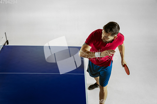 Image of Young man playing table tennis on white studio background