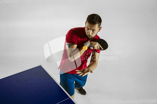 Image of Young man playing table tennis on white studio background