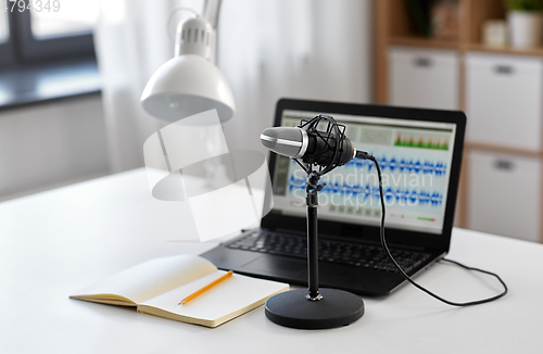 Image of microphone, laptop and notebook on table