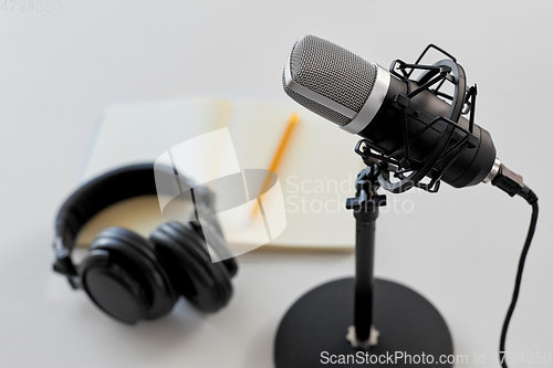 Image of headphones, microphone and notebook with pencil