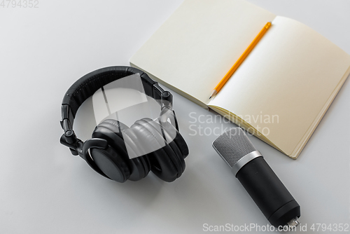 Image of headphones, microphone and notebook with pencil