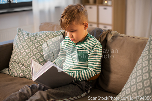 Image of little boy reading book at home