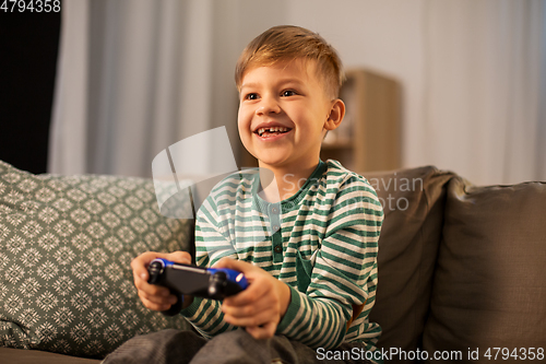 Image of little boy with gamepad playing video game at home