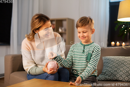 Image of mother and little son with piggy bank at home