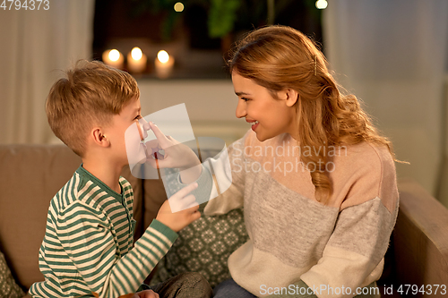 Image of happy mother touching little son's nose at home