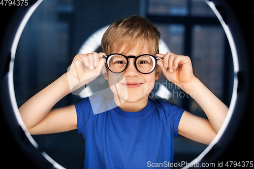 Image of boy in glasses over illumination in dark room