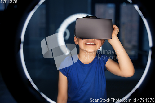 Image of boy in vr glasses over illumination in dark room