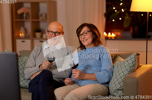Image of happy senior couple drink red wine and watch tv