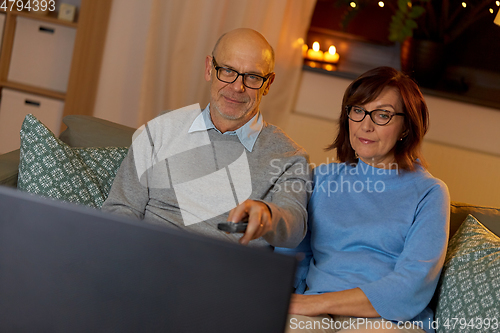 Image of senior couple watching tv at home in evening