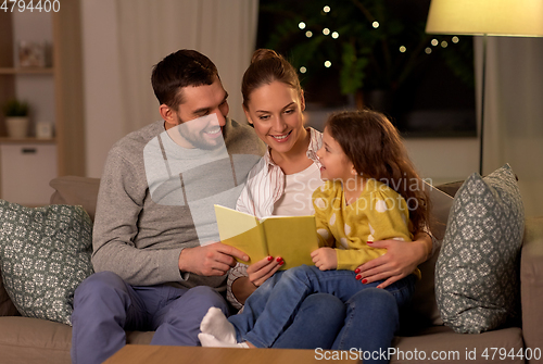 Image of happy family reading book at home at night