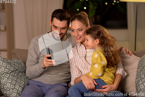 Image of happy family with smartphone at home at night