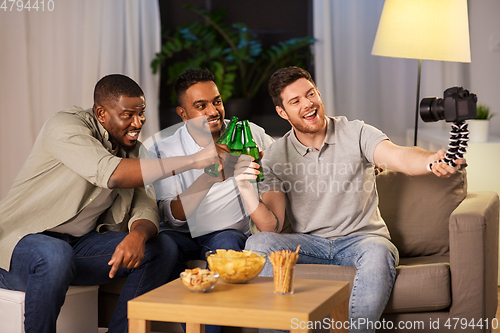 Image of male video blogger with friends and camera at home