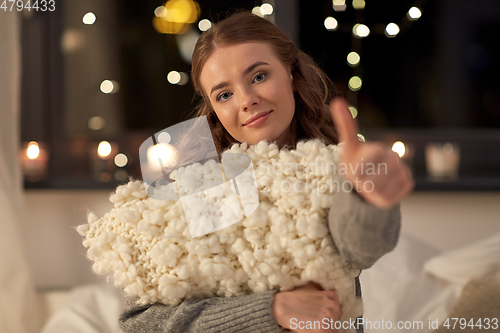 Image of happy young woman with soft pillow in bed at home