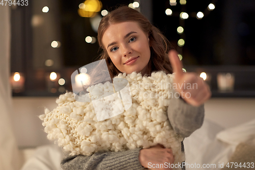 Image of happy young woman with soft pillow in bed at home