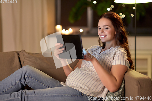 Image of happy pregnant woman with tablet pc at home