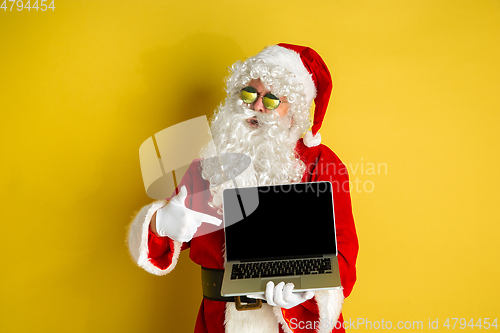 Image of Santa Claus with modern gadgets isolated on yellow studio background