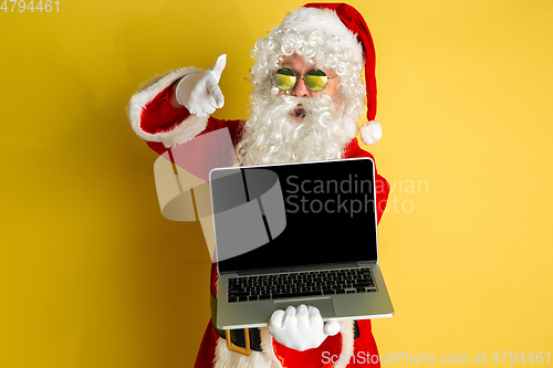 Image of Santa Claus with modern gadgets isolated on yellow studio background