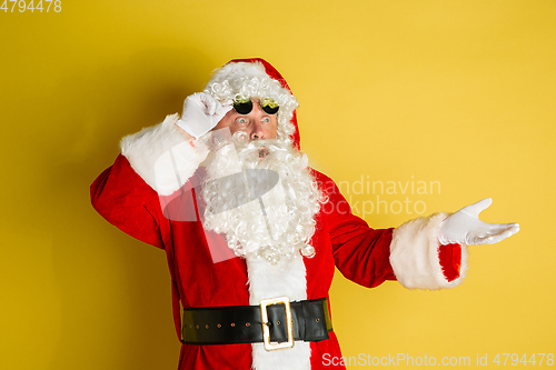 Image of Santa Claus with modern eyeglasses isolated on yellow studio background