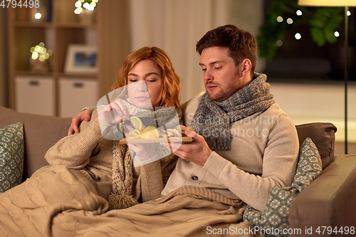 Image of sick young couple drinking tea with lemon at home