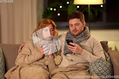 Image of sick young couple with smartphone at home