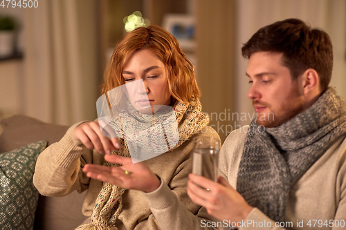 Image of sick couple taking medicine at home