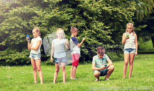 Image of kids with smartphones playing game in summer park