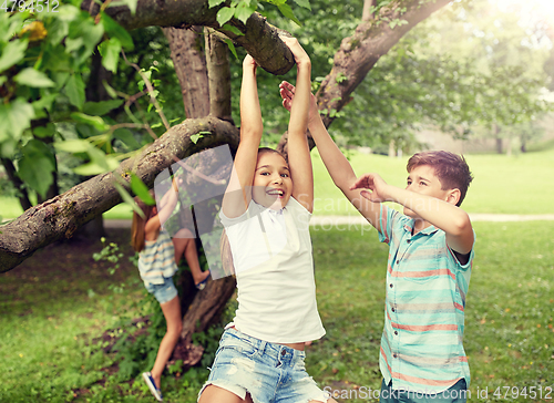 Image of happy kids hanging on tree in summer park
