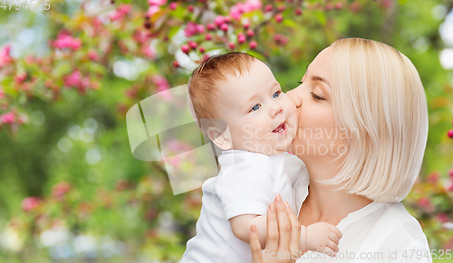 Image of close up of happy mother kissing baby over garden