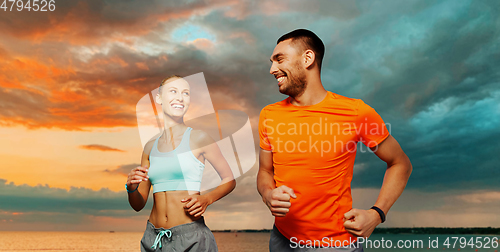 Image of smiling couple running over sea