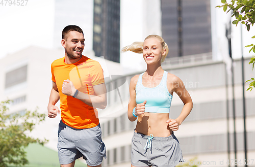 Image of happy couple with fitness trackers running at city