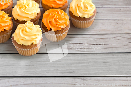 Image of cupcakes with frosting on wooden boards background