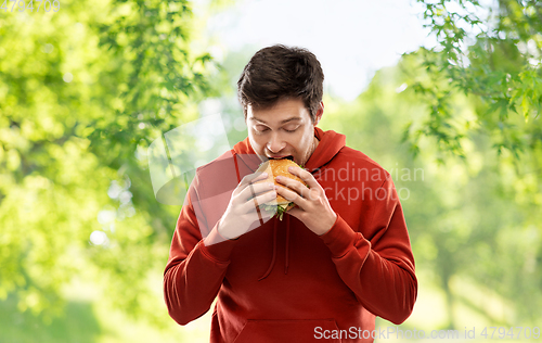 Image of hungry young man eating hamburger