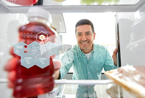 Image of man taking juice from fridge at home kitchen