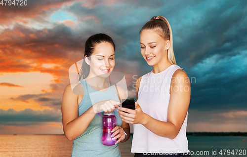 Image of women or female friends with smartphone and flask