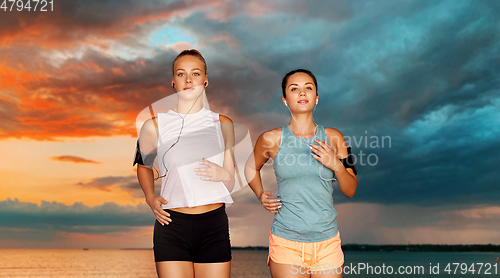 Image of young women with earphones and smartphones running