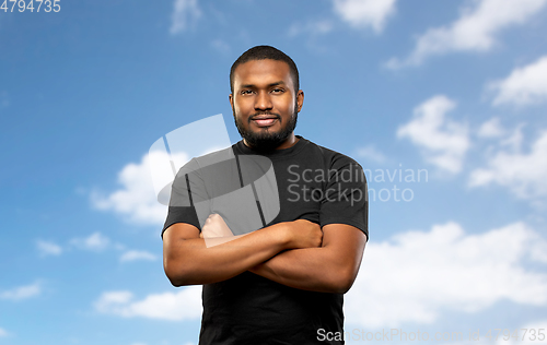 Image of african american man with crossed arms over sky