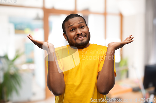 Image of african american man in yellow t-shirt shrugging