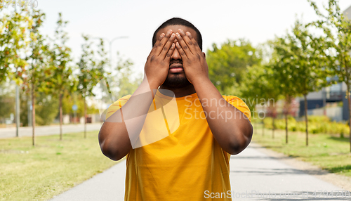 Image of african american man closing his eyes by hands