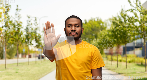 Image of african american man showing stop gesture outdoors