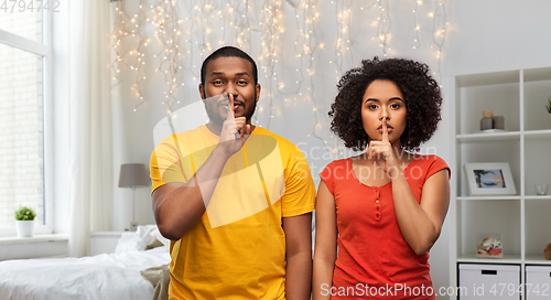 Image of happy african american couple making hush gesture