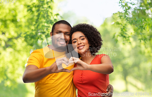 Image of happy african american couple making hand heart