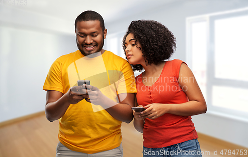 Image of happy african american couple with smartphones