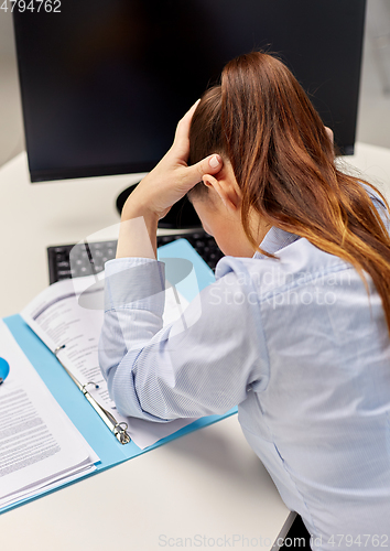 Image of stressed businesswoman with papers at office