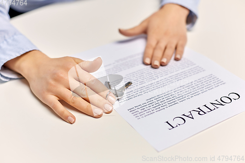 Image of realtor's hands with keys and contract on table