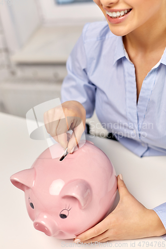 Image of businesswoman with piggy bank and coin at office