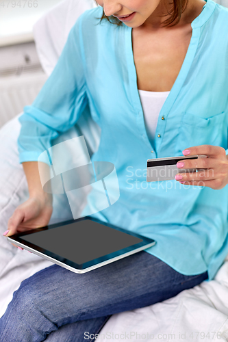 Image of happy woman with tablet pc and credit card at home