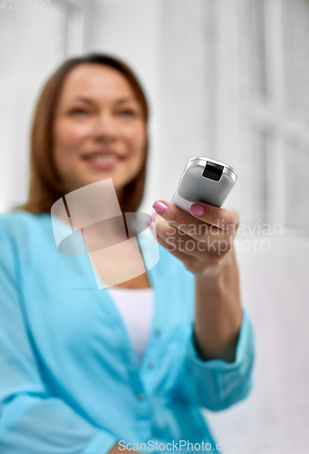 Image of close up of woman with tv remote control at home