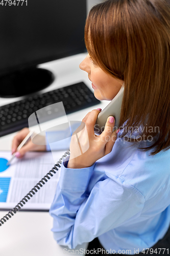 Image of businesswoman calling on desk phone at office