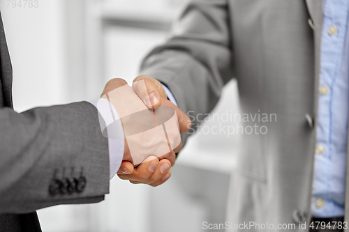 Image of close up of businessmen making handshake at office
