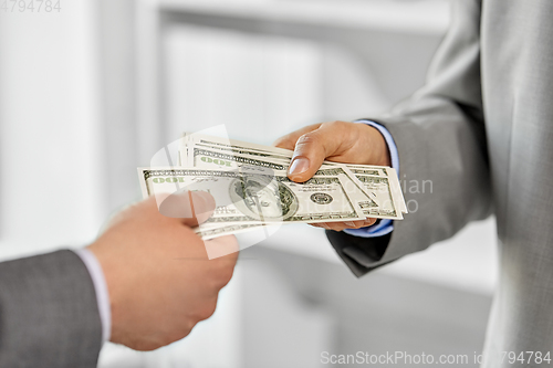 Image of close up of businessmen's hands holding money